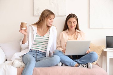 Yurt odasında dizüstü bilgisayarla çalışan kız öğrenciler.