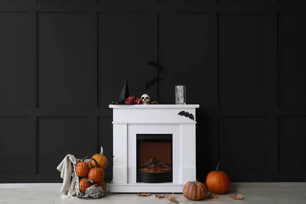 Fireplace decorated for Halloween party near black wall in room