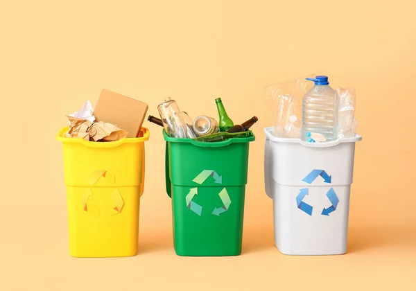 Containers with different types of garbage on beige background. Recycling concept