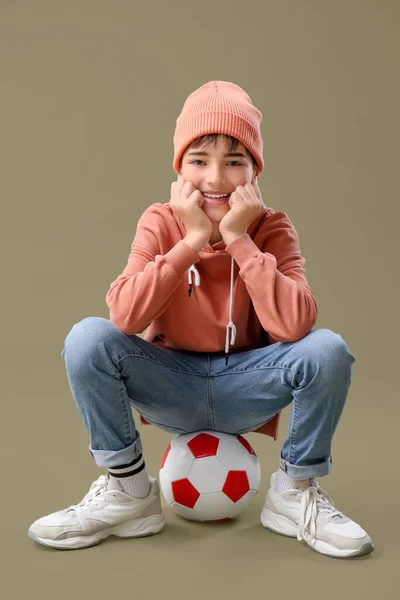 Kleiner Junge Sitzt Auf Fußball Vor Farbigem Hintergrund — Stockfoto