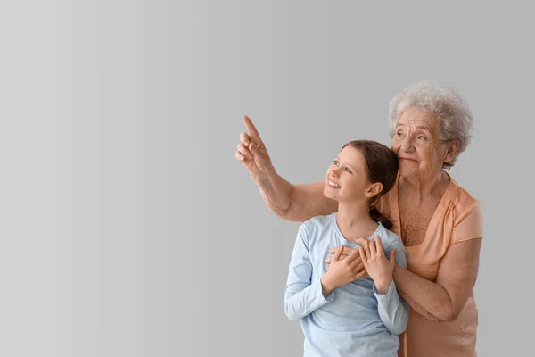 Klein Meisje Met Haar Oma Wijzend Naar Iets Grijze Achtergrond — Stockfoto