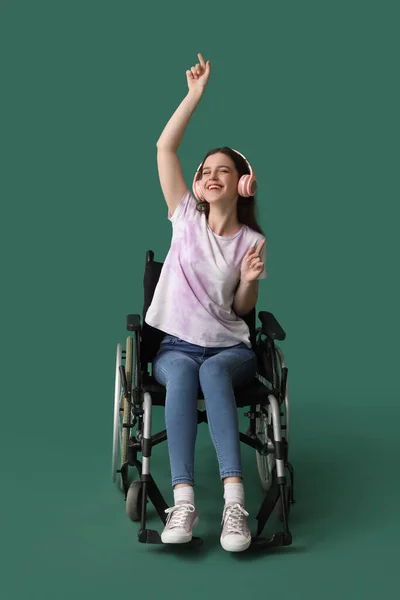 Молодая Женщина Наушниками Инвалидной Коляске Зеленом Фоне — стоковое фото