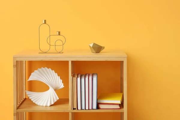 Shelving unit with books and decor near orange wall in room, closeup