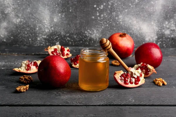 Rosh Hashanah kutlaması için nar ve elmalı bal kavanozu (Yahudi Yeni Yılı) siyah ahşap masada