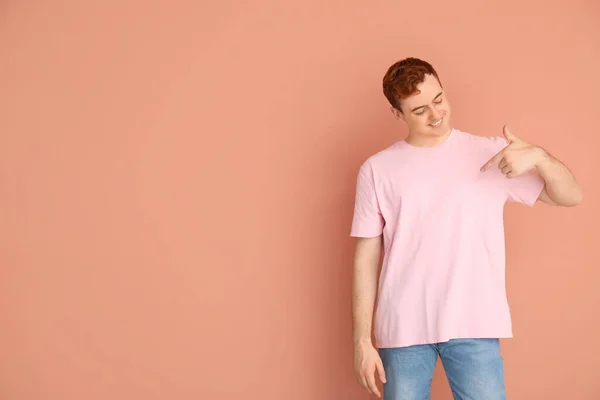 Junger Mann Zeigt Auf Sein Shirt Auf Beigem Hintergrund — Stockfoto