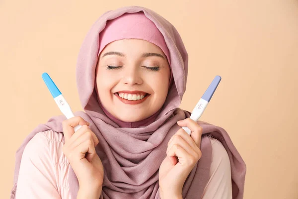 ベージュの背景で肯定的な妊娠テストを持つ幸せなムスリムの若い女性 — ストック写真