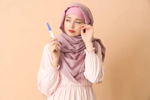 ベージュの背景で妊娠検査を受けるイスラム教徒の若い女性を心配 — ストック写真