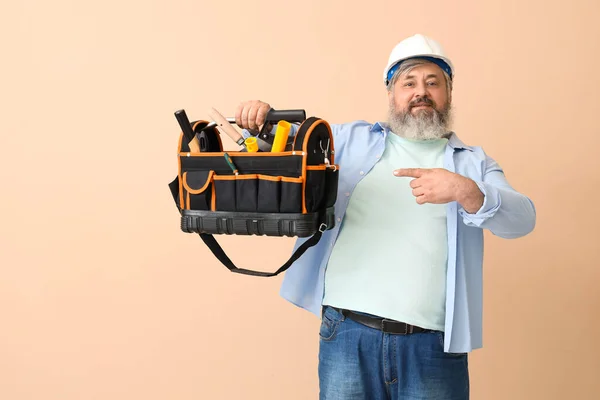Portrait Senior Man Hardhat Pointing Bag Tools Beige Background Labor — Stock Photo, Image