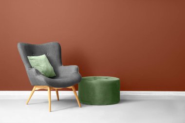 Yastıklı ve kahverengi duvarlı şık gri koltuk.