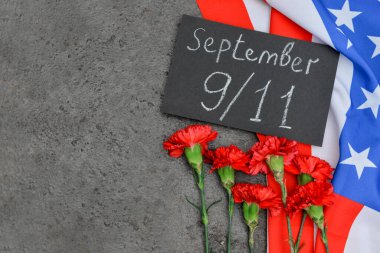 Ulusal Namaz Günü tarihi ve terör saldırıları kurbanları için anma kartı, karanfil çiçekleri, grunge gri arka planda ABD bayrağı