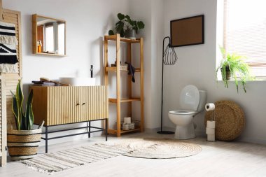 Modern tuvaletin içinde seramik klozet ve ahşap dolap var.