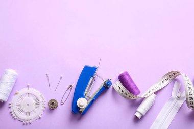 Leylak arka planında farklı malzemelerle elle dikiş makinesi.