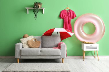 Yeşil duvarın yanında plaj aksesuarları olan şık bir oturma odası.