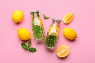 Pembe arka planda naneli lezzetli limonata şişeleri.