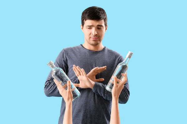 Молодой Человек Отвергает Бутылки Водки Голубом Фоне — стоковое фото