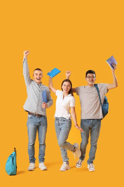 Счастливые Студенты Рюкзаками Блокнотами Желтом Фоне — стоковое фото