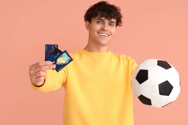 サッカーボールとピンクのバックグラウンドのクレジットカードを持つ若い男 スポーツベットコンセプト — ストック写真