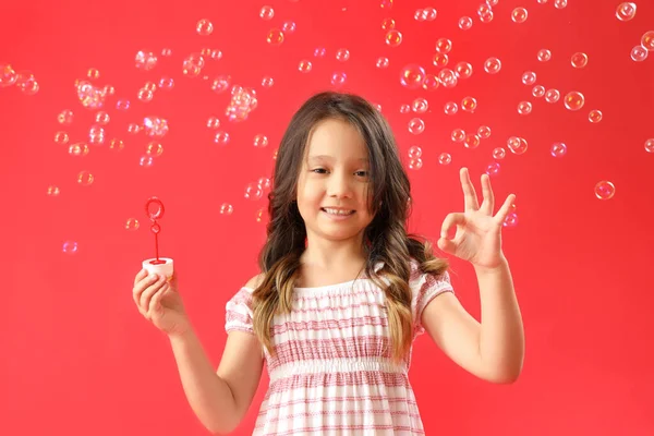 可爱的小女孩 红色背景的肥皂泡 — 图库照片