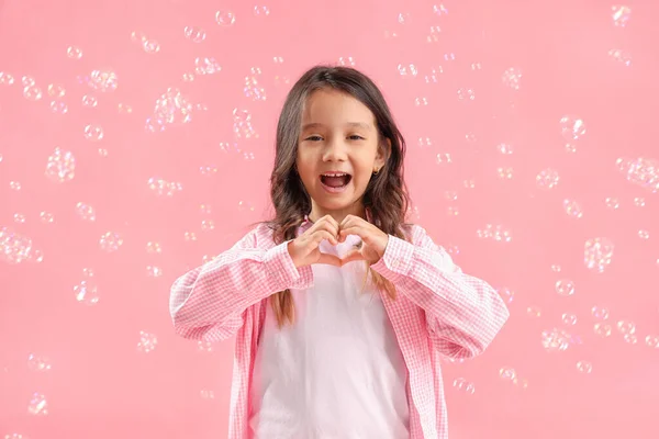 Симпатична Дівчинка Робить Серце Руками Мильними Бульбашками Рожевому Фоні — стокове фото