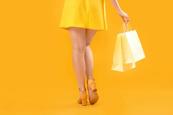 オレンジ色の背景のショッピングバッグを持つ女性 バックビュー — ストック写真