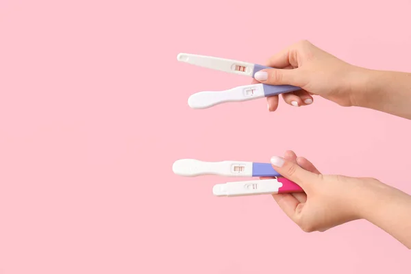 Weibliche Hände Mit Verschiedenen Schwangerschaftstests Auf Rosa Hintergrund — Stockfoto