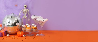 Cadılar Bayramı partisi için eflatun arkaplanlı yaratıcı kokteyller ve kekler. Tasarım için pankart