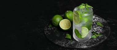 Koyu arkaplanda bir bardak taze mojito ve limon. Tasarım için pankart
