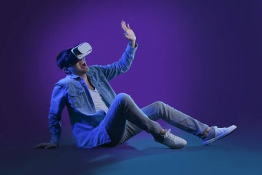 Young man using VR glasses on dark color background