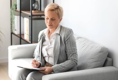 Ofisinde evrakları olan olgun bir iş kadını.