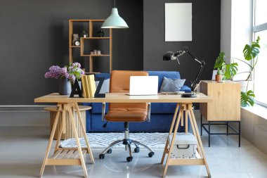 Interior of living room with stylish holder for books and lilac flowers on table clipart