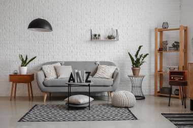 Oturma odasının içinde kanepe, ev bitkileri ve sehpanın üzerindeki kitaplar için şık bir tutucu var.