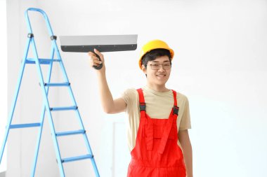 Odasında macun bıçağı olan Asyalı dekoratör.