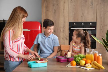 Anne, küçük çocuklarına mutfakta öğle yemeği hazırlıyor.