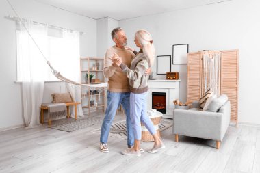 Evde şöminenin yanında dans eden olgun bir çift.