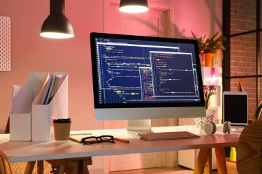 Karanlık ofisin içinde cihazları olan programcının çalışma yeri