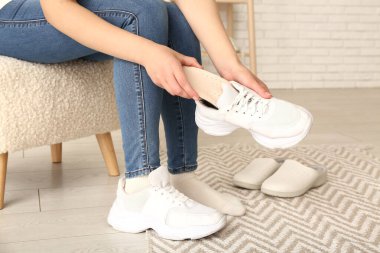 Kadın evde spor ayakkabısına ortopedik taban takıyor.
