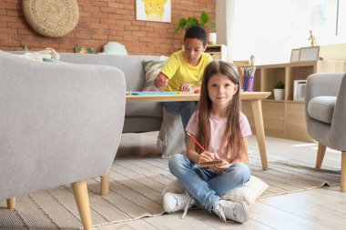 Evdeki defterde küçük şirin bir kız resmi çiziyor.