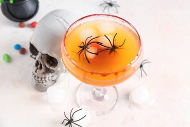 Cadılar Bayramı için bir bardak lezzetli Margarita kokteyli ve arka planda kafatası.