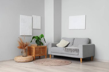 Modern oturma odasının içinde resimler, gri kanepe ve çiçek var.