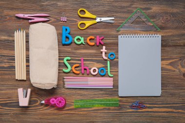 Text BACK TO SCHOOL and stationery on wooden background