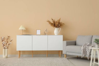 Gri kanepesi ve beyaz büfesi olan şık bir oturma odası.