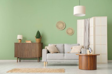 Gri kanepesi, sehpası ve ahşap dolabı olan şık bir oturma odası.