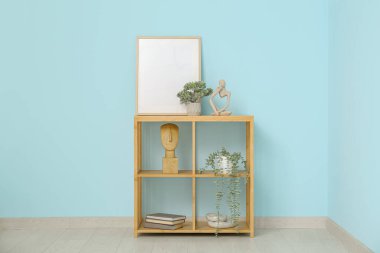 Mavi duvarın yanında boş çerçeve ve dekora sahip raf ünitesi
