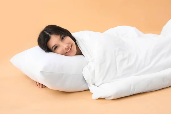 Красивая Счастливая Молодая Женщина Подушкой Мягким Одеялом Лежит Бледно Оранжевом — стоковое фото