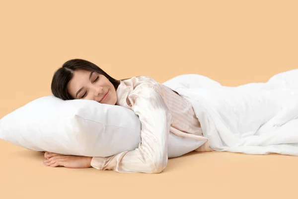 美丽而快乐的年轻女子 枕头和柔软的毛毯睡在苍白的橙色背景下 — 图库照片