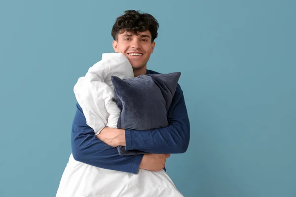 英俊快乐的年轻人 有柔软的毛毯和蓝色背景的枕头 — 图库照片