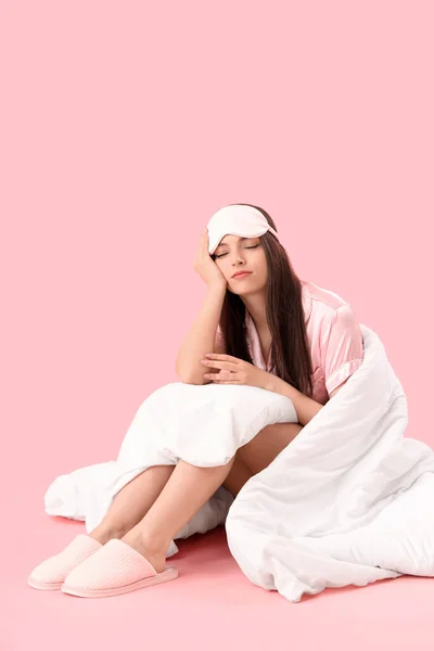 眠いです若いです女性とともに柔らかい毛布上に座ってピンクの背景 — ストック写真