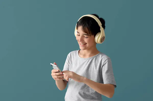 Mały Chłopiec Słuchawkach Pomocą Telefonu Komórkowego Niebieskim Tle — Zdjęcie stockowe