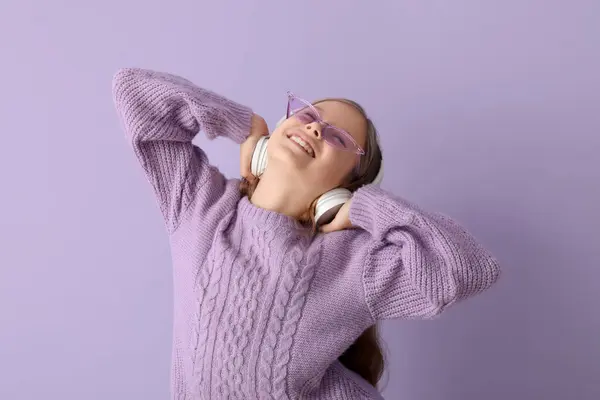 Kulaklıklı Küçük Kız Leylak Arka Planda Müzik Dinliyor — Stok fotoğraf