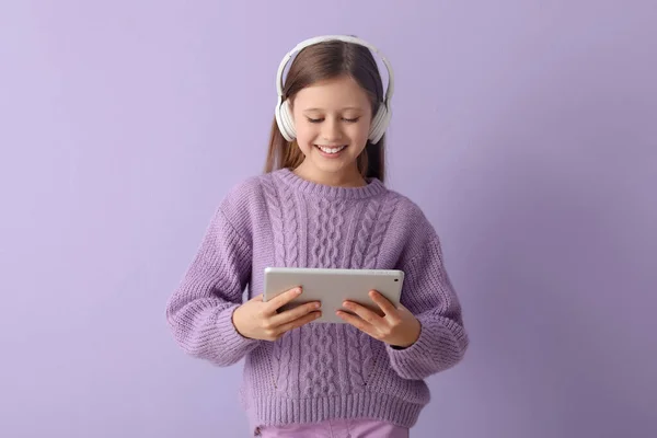 Kulaklıklı Küçük Kız Eflatun Arka Planda Tablet Bilgisayar Kullanıyor — Stok fotoğraf